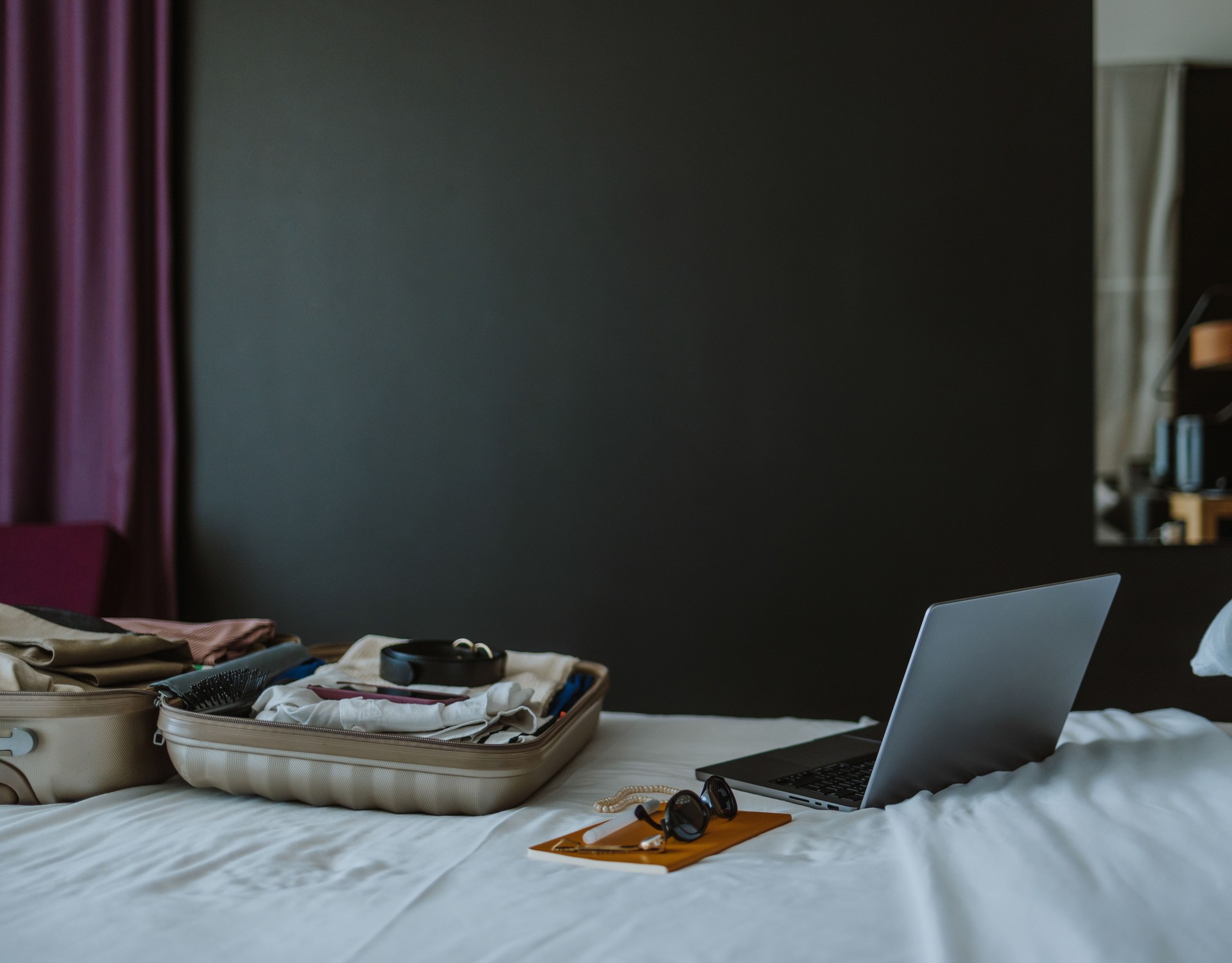 Laptop and Open Suitcase on the Bed in the Hotel Room