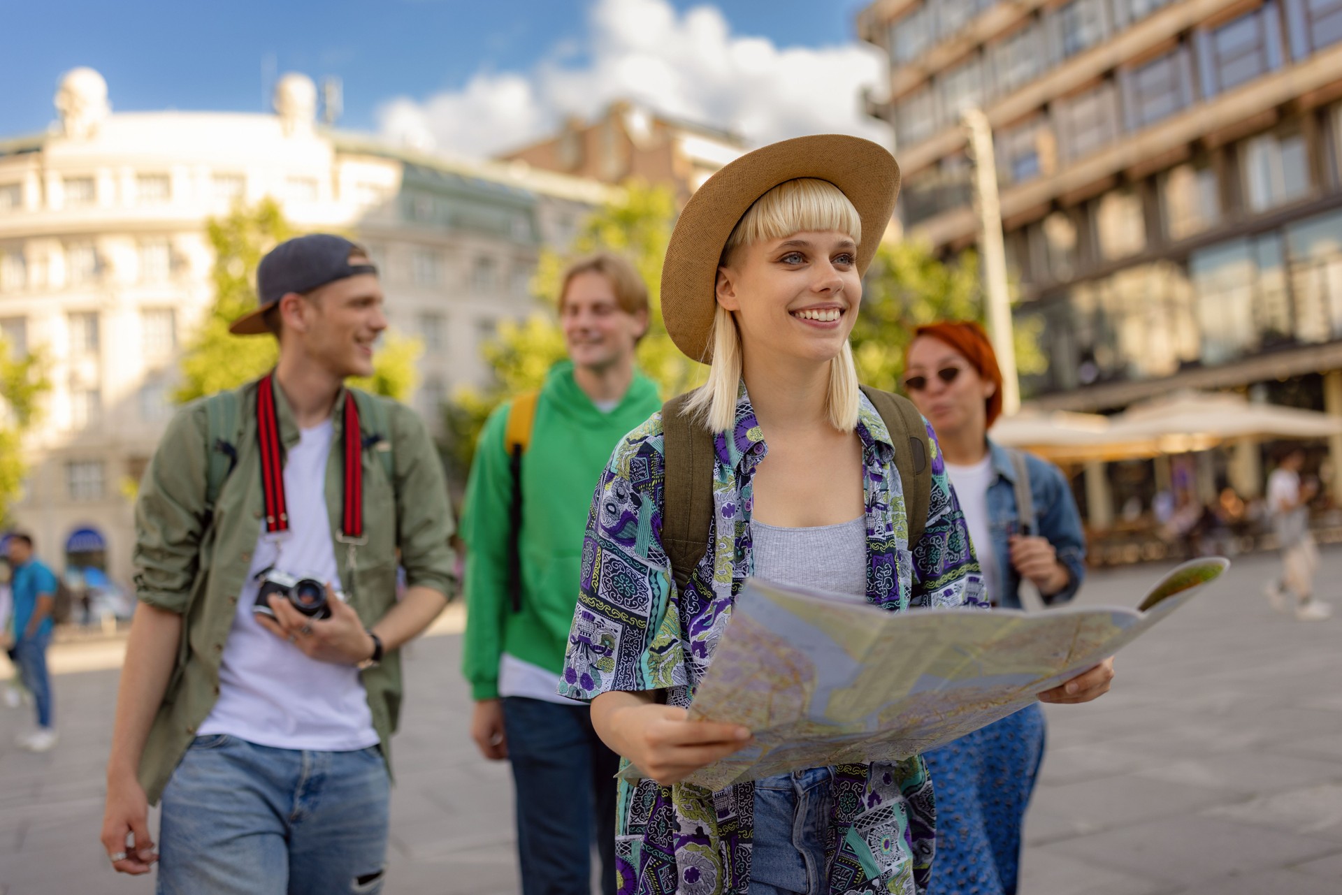 Happy female tourist reading a map while exploring the city with her friends.