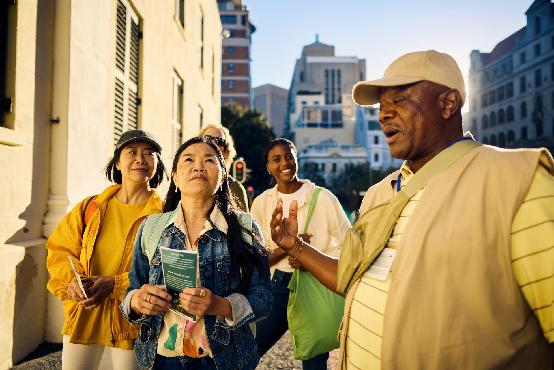 Diverse group of tourists on a city tour with guide. Outdoor urban setting with people listening to a guide. Travel and exploration concept.